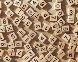 Drewniane kafelki z cyframi i symbolami matematycznymi, jakby ktoś uczył się dzielenia w słupku.