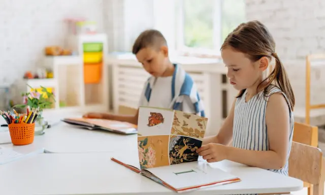Dzieci uczą się dzielenia do 100, przeglądając książkę z ilustracjami owadów i kwiatów.